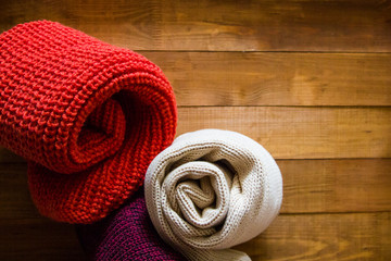Knitted scarves on wooden background
