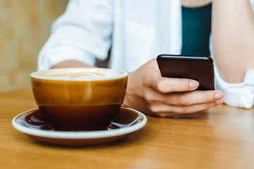 Close up of woman hands holding cell telephone, blogger girl watching video, writing message, on mobile phone during coffee break