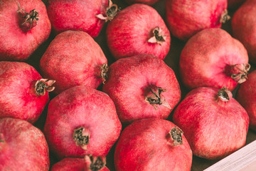 Ripe juicy red pomegranates on the wooden shelf. Harvest and sell of organic fresh fruits.