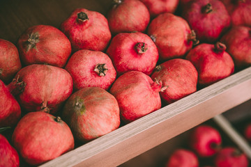 Ripe juicy red pomegranates on the wooden shelf. Harvest and sell of organic fresh fruits.