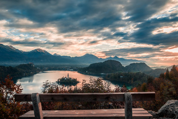 View of famous wooden bench and lake Bled with Alps mountains in background