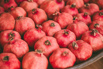 Fototapeta na wymiar Ripe juicy red pomegranates on the wooden shelf. Harvest and sell of organic fresh fruits.