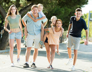 Obraz premium Smiling parents with kids taking fast promenade