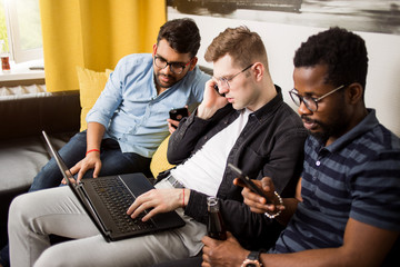 Group of friends sitting on sofa with laptop