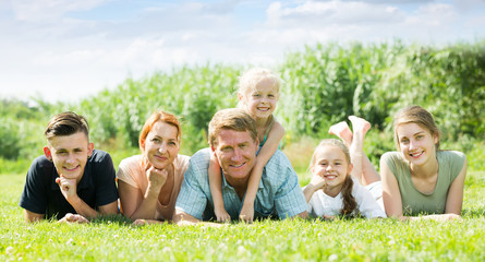 Portrait of modern large family lying together on green lawn outdoors