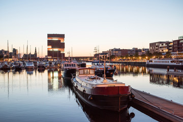 Fototapeta na wymiar Night view of modern Eilandje area and port in Antwerp, Belgium. Small island district and sailing marine at sunset. Popular travel destination and tourist attraction