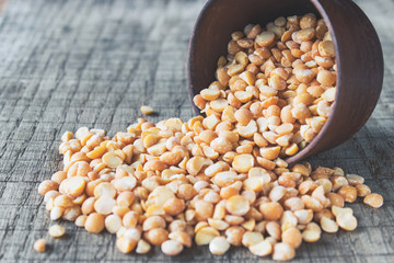 Dry yellow peas in a bowl on old boards. Chipped yellow peas are used for cooking.