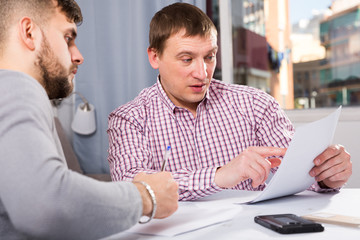 Focused man with partner reading papers at table