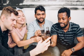 Cheerful multi-ethnic friends sitting on sofa