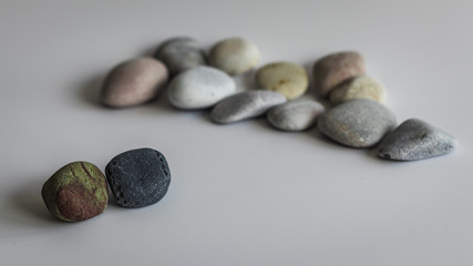 The concept of exclusion from the group made using colored stones on a white background. A reference to racism and religious, sexual or ideological intolerance.