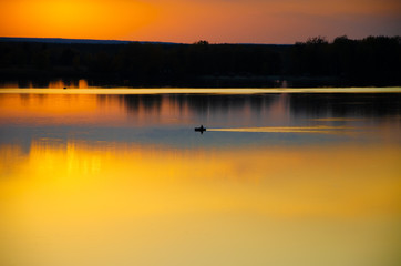 sunset on the lake and the boatman swims