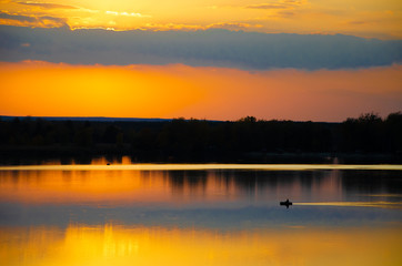 Fototapeta na wymiar sunset on the lake and the boatman swims