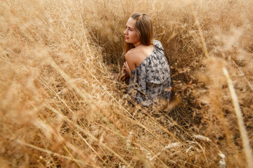 Naklejka na ściany i meble beautiful young girl is on wheat field in sunny day. An seductive girl with long light hair walk in the wheat field portrait ihappy girl in field with spikelets landscape. weekend outdoors in summer.