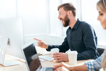 smiling businessman talking to a colleague sitting at his Desk