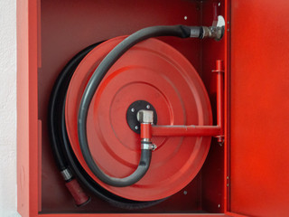 Wall mounted fire water hoses and fire fighting equipment on red cabinet