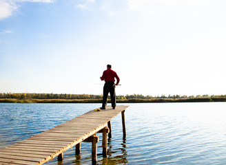 fisherman on a bridge near a blue lake