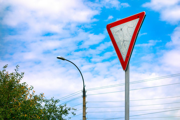 Give way road sign against cloudy sky.