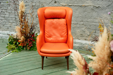 Orange faux leather chair on the outdoor loft-style terrace.The composition of the casual arrangement of Japanese pampas grass.