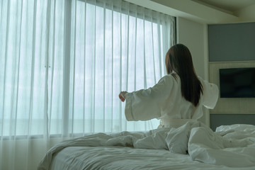 Fototapeta na wymiar Behide asian woman in bathrobe suit wake-up on a bed in the hotel, Travel and Holiday concept