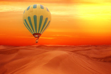 Desert landscape view with flying hot air balloon, sand dunes, bright red sunset.