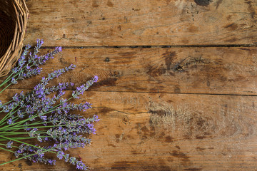 Bouquet of lavender flowers and wicker basket on the vintage wooden background with copy space