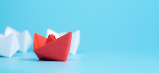 Leadership concept. Red leader paper ship leading among white on blue background. copy space