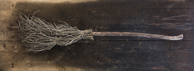 halloween witch broom on black wooden background