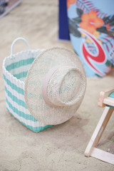 starw hat. straw hat and woven basket on the beach, next to beach chair and surf board on the...