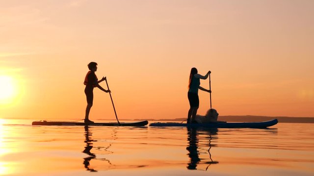 Sunset lake with mom and son riding paddleboards