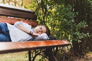 Woman sleeping on a bench outdoors