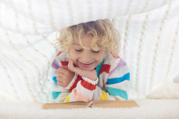 Fototapeta premium Child reading book in bed. Kids read books.