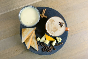 Cheese coffee with melted cheese, pieces of cheese and bread toasts on a tray