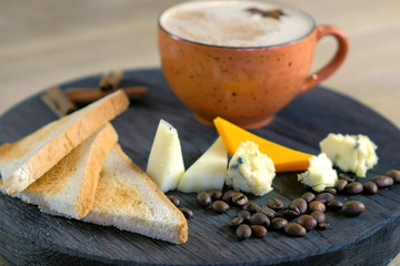 Cheese coffee with melted cheese, pieces of cheese and bread toasts on a tray, side view.