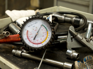 Pressure gauge and other working tools on a car service desk