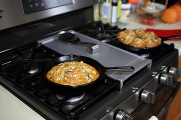 Banana nut bread with berries fresh out of the oven, baked in cast iron cookware in a home kitchen.