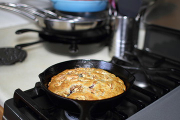 Banana nut bread with berries fresh out of the oven, baked in a cast iron skillet in a home kitchen.