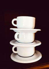 Set of white cups in a cupboard, piled