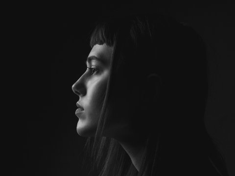 Portrait of young woman in profile. Low key. Black and white.