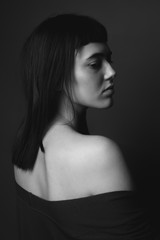 Portrait of attractive young woman with bare shoulders. Black and white. From back
