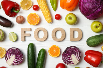 Word Food laid out of wooden letters, vegetables and fruits on wood background, top view