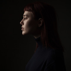 Portrait of young woman in profile. Low key. Close up