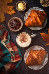 cappuccino coffee with croissant on the table, autumn breakfast concept, top view