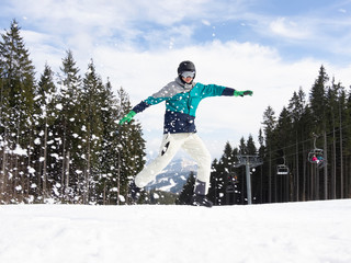 The guy snowboarder jumping on mountain slope