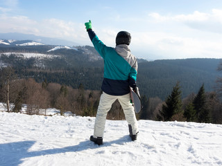 The guy is a snowboarder enjoying a view of the ski resort