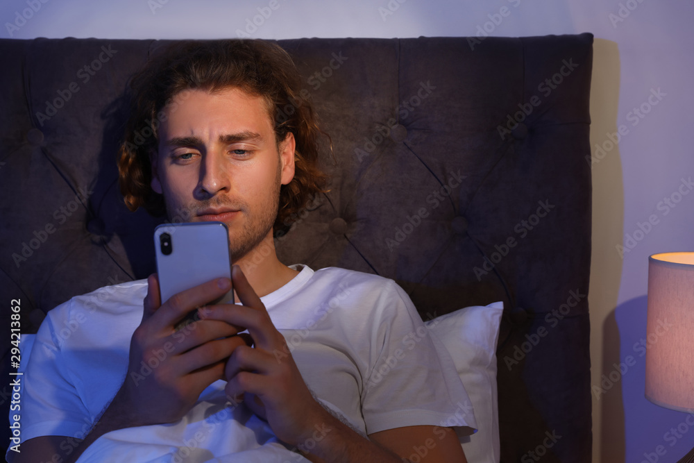 Canvas Prints Handsome young man using smartphone in dark room at night. Bedtime