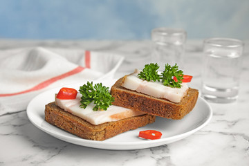 Plate with pork fatback sandwiches and shots of vodka on marble table