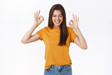 Excited, joyful happy young woman in yellow t-shirt think party is awesome, having fun, enjoying nice atmosphere, close eyes and smiling pleased, showing okay, ok gesture, white background