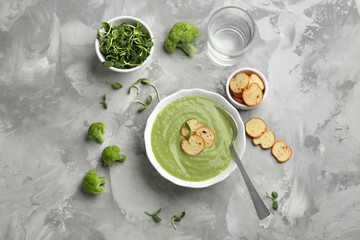 Flat lay composition with bowl of broccoli cream soup on grey table