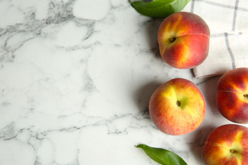 Fresh peaches, leaves and fabric on marble table, flat lay. Space for text