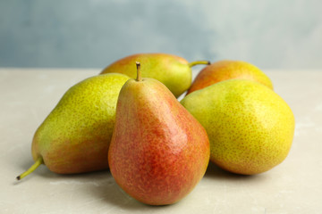 Heap of ripe juicy pears on light stone table against blue background